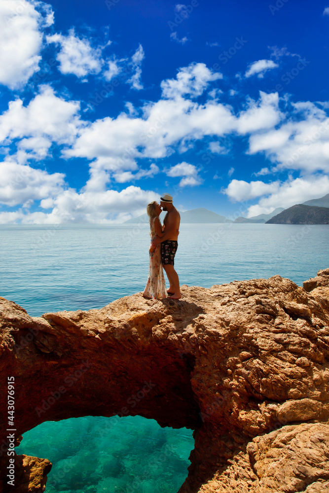 Loving couple enjoying honeymoon on rock with luxury view