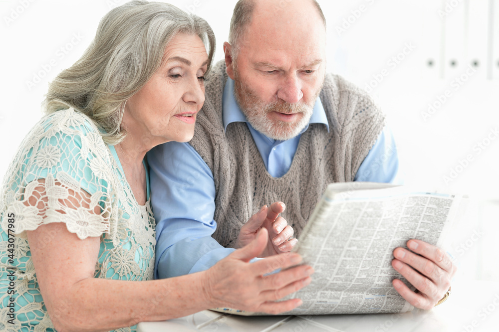 Close-up portrait of a senior couple with newspaper at home Close-up portrait of a senior couple with newspaper at home