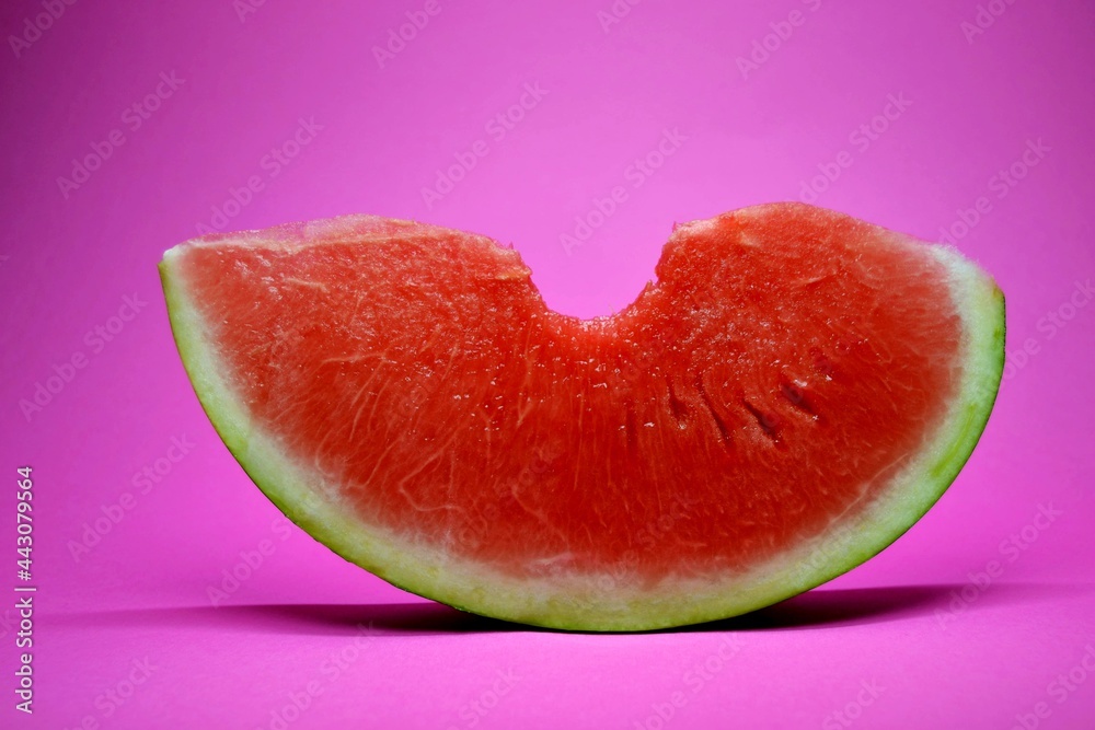 Fresh bitten watermelon slice isolated on a pink background