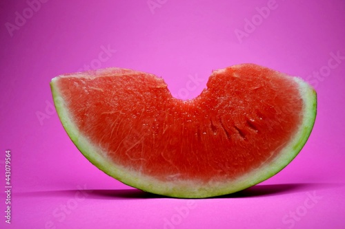 Fresh bitten watermelon slice isolated on a pink background