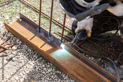 A welder welds metal at a construction site.
