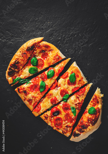 flatbread Pizza with Mozzarella cheese, Tomatoes, pepper, Spices and Fresh Basil. Italian pizza. Pizza Margherita or Margarita on Dark grey black slate background