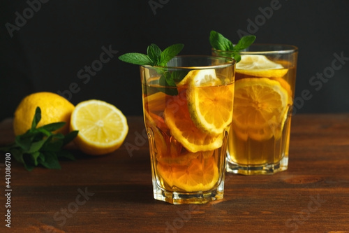 Two glasses with traditional iced tea with lemon and mint leaves in glass on the wooden rustic background