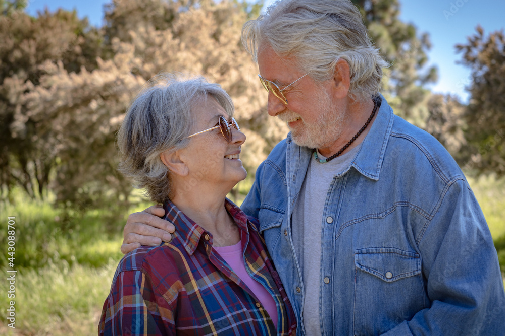 Beautiful elderly couple embraced in the wood looking each other in the eyes. Two married people enjoying retirement lifestyle Beautiful elderly couple embraced in the wood looking each other in the eyes. Two married people enjoying retirement lifestyle