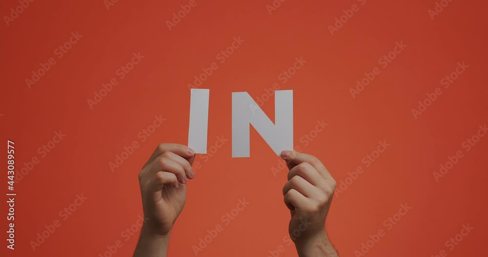 Hands raising up showing letters in of english language. Man shows preposition in made of carved paper
