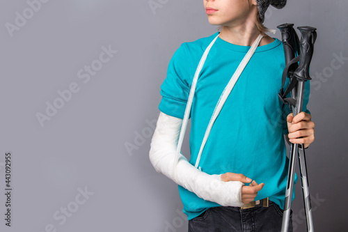 Handsome boy with broken arm over grey background