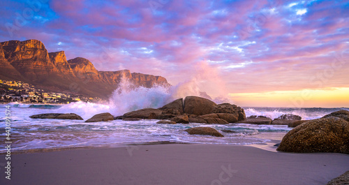 Beautiful sunset as waves crash on the rocks at Maiden's Cove beach, Camps Bay. The Twelve Apostles Mountain Range is where you'll find one of most scenic stretches of coast in the world photo