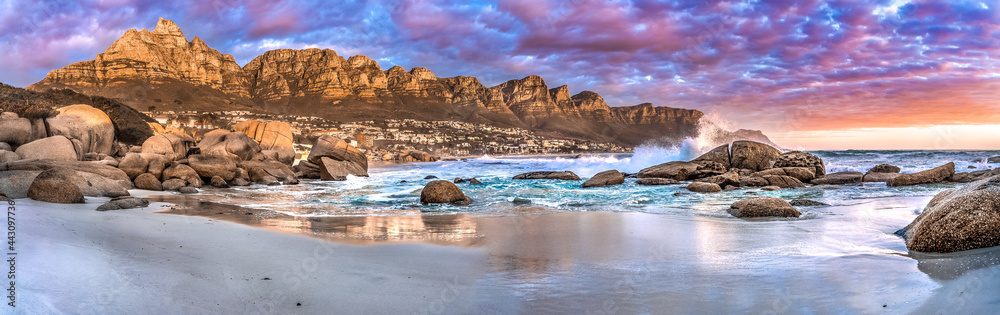 Naklejka premium Breathtaking sunset panorama of the iconic Table Mountain and the Twelve Apostles range, Cape Town South Africa. A unique and scenic wide-angle perspective taken from Maidens cove beach