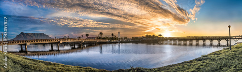 Beautiful sunset vista of Milnerton bridge, lighthouse and lagoon set on a backdrop of Table Mountain under a breathtaking orange sky