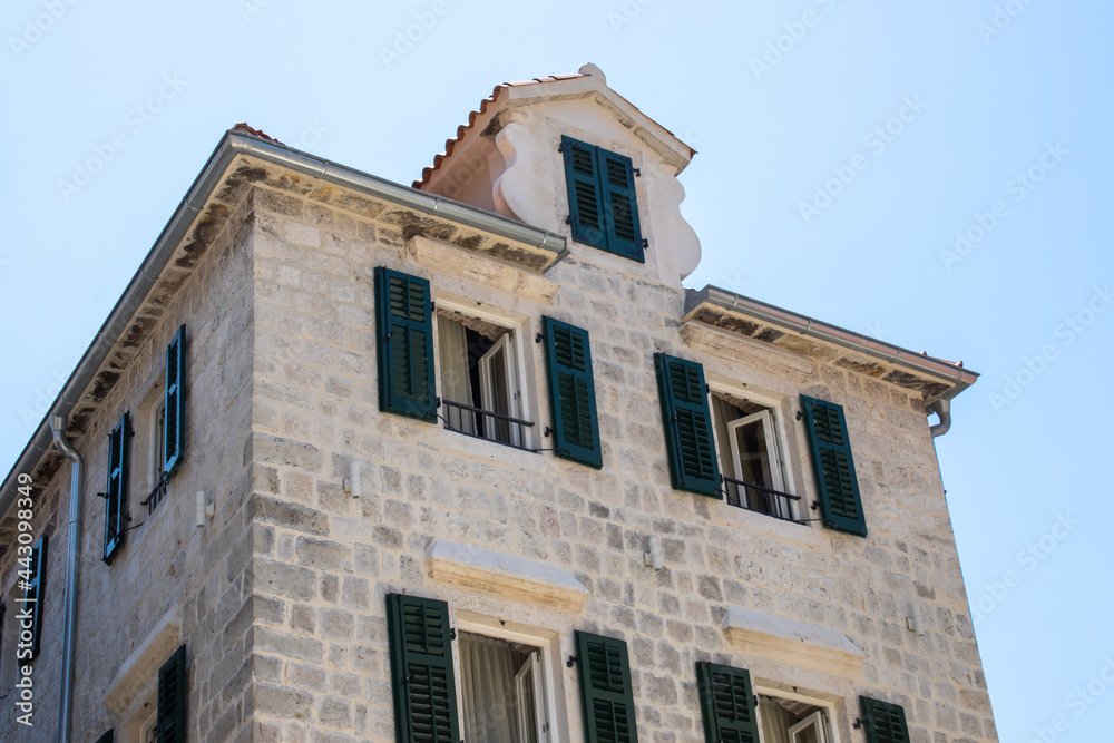 Fototapeta premium Medieval buildings. Old town of Kotor Montenegro on the blue sky background. An old building with open windows.