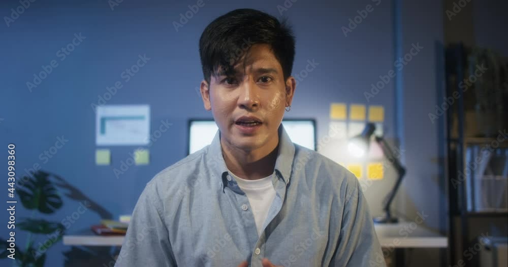 Young Asian business man on video online conference call, look at camera, remote team meeting at night. Work from home office, internet technology, coronavirus social distancing lifestyle concept Young Asian business man on video online conference call, look at camera, remote team meeting at night. Work from home office, internet technology, coronavirus social distancing lifestyle concept