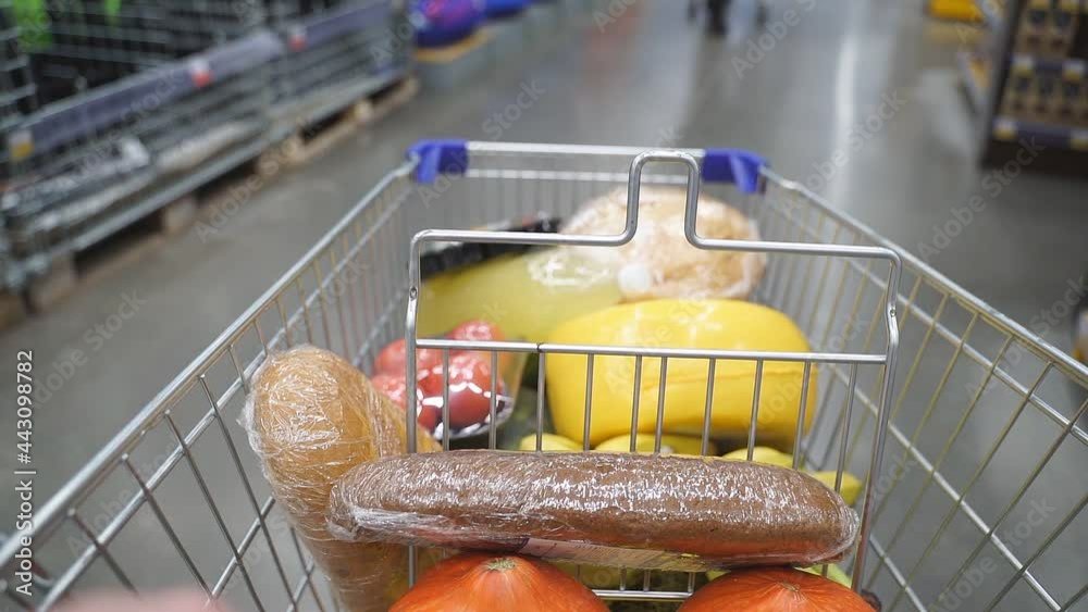 Shopping cart moving between various section in Supermarket. Inside trolley various healthy items and convenience food.