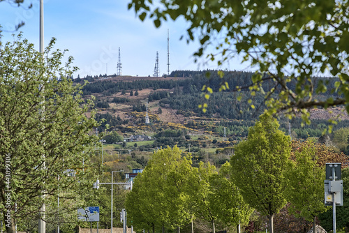 Beautiful closeup creative view of Three Rock TV transmitter antennas among spring leaves viewed from Ballinteer, Dublin, Ireland. Cellular towers. Creative shot