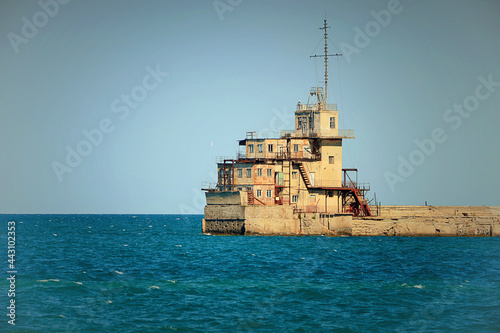 A beautiful shot of a old lighthouse in the sea with the blue sky and in the background