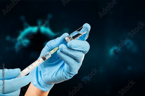 octor's hand in blue gloves hold medicine vaccine vial bottle and syringe. 