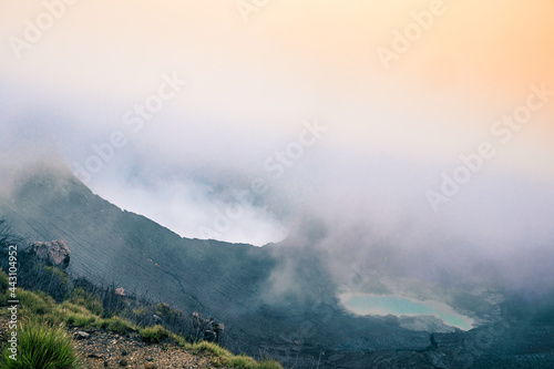 View of the viewpoint of the Turrialba Volcano National Park and main crater on the left and a turquoise volcanic lagoon on the right on a foggy day near the cloud forest of Costa Rica