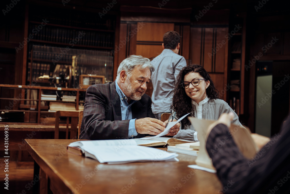 Senior professor working with female student in the library