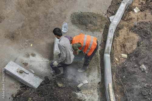 Handyman in an orange vest. Preparatory work for the installation of street curbstone