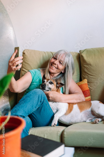 Elder woman taking a selfie with dog using a smartphone