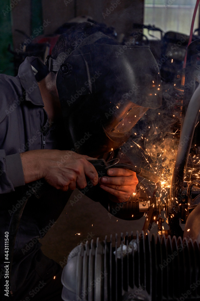 Anonymous mechanic welding parts of motorcycle Anonymous mechanic welding parts of motorcycle