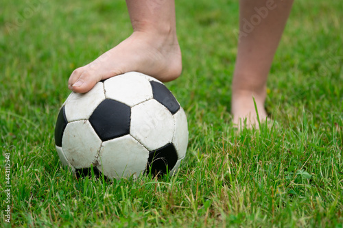 Bare foot of a girl on the soccer ball in green grass © Georgy Dzyura