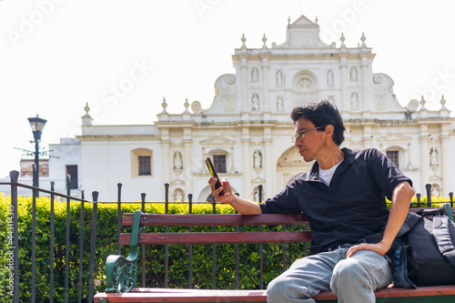 Hispanic man sitting in front of main cathedral in antigua guatemala photo