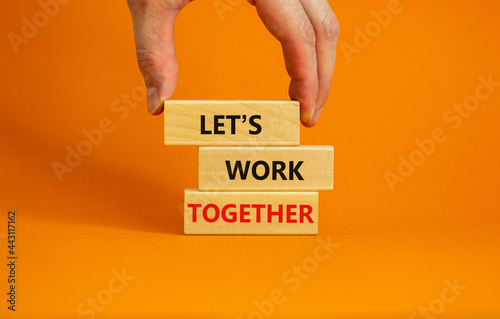 Work together symbol. Wooden blocks with words Let is work together on beautiful orange background. Businessman hand. Business, let is work together concept. Copy space.