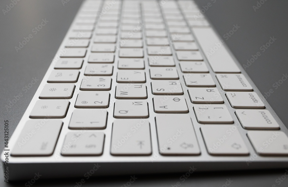 The wireless keyboard is white on a gray background with a place for text. English-Russian layout. High quality photo The wireless keyboard is white on a gray background with a place for text. English-Russian layout. High quality photo