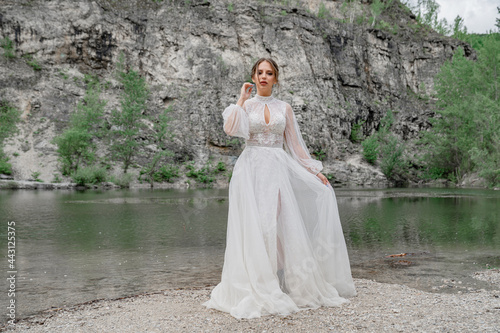 The bride in a white wedding dress on the bank of a mountain river.