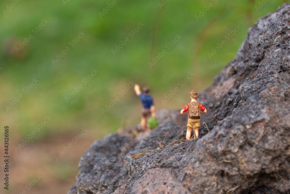 miniature figures of people hiking on a rock