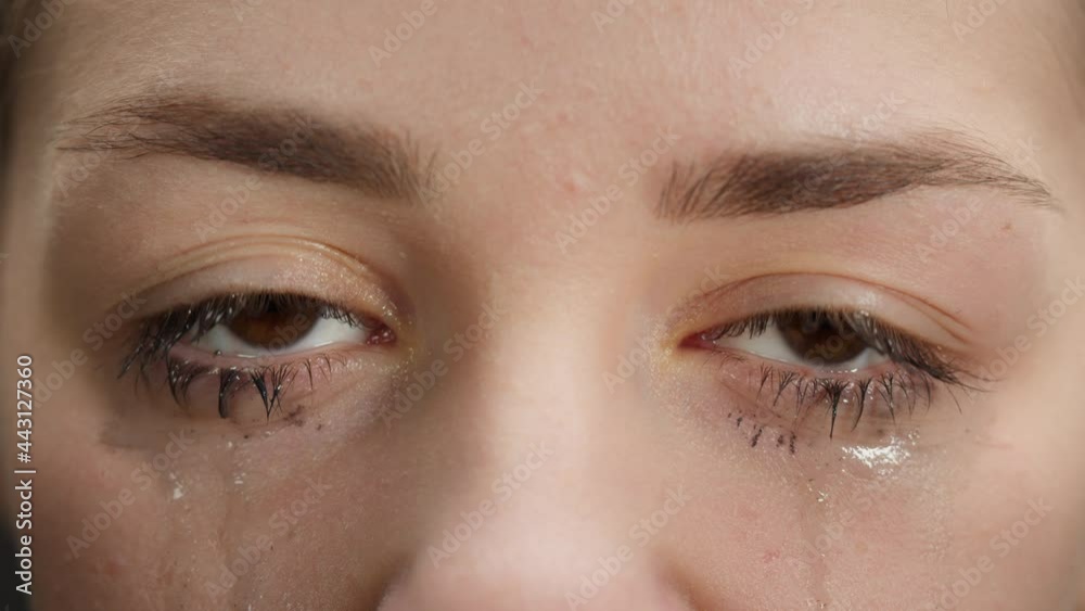Closeup of crying brown eyes, smeared mascara, watery eye of young woman, shooting of tears