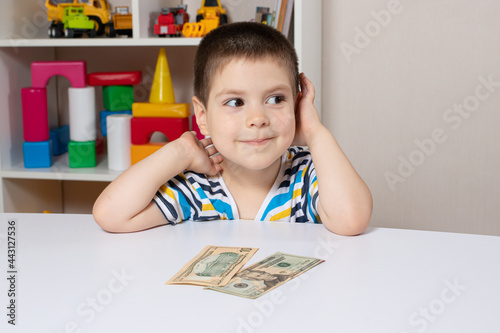 A beautiful child and dollar bills. The boy is thinking about where to spend the money. Financial literacy for children