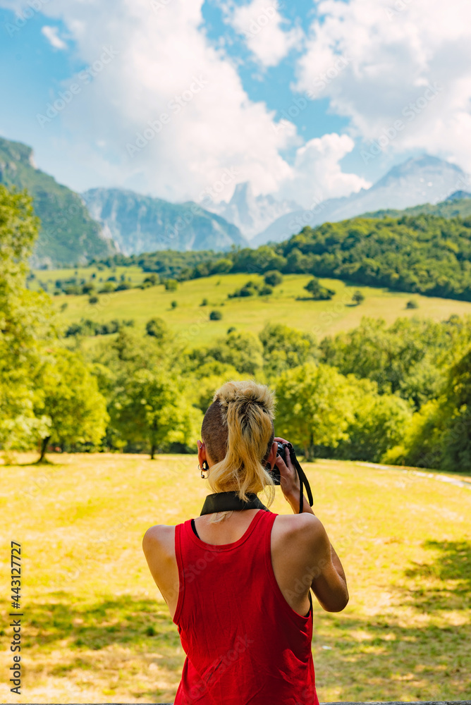 Young girl from behind with red shirt taking photograph of the mountainous landscape of the 
