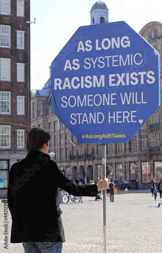 Amsterdam Dam Square with Young Man Holding a Protest Sign Against Systemic Racism photo