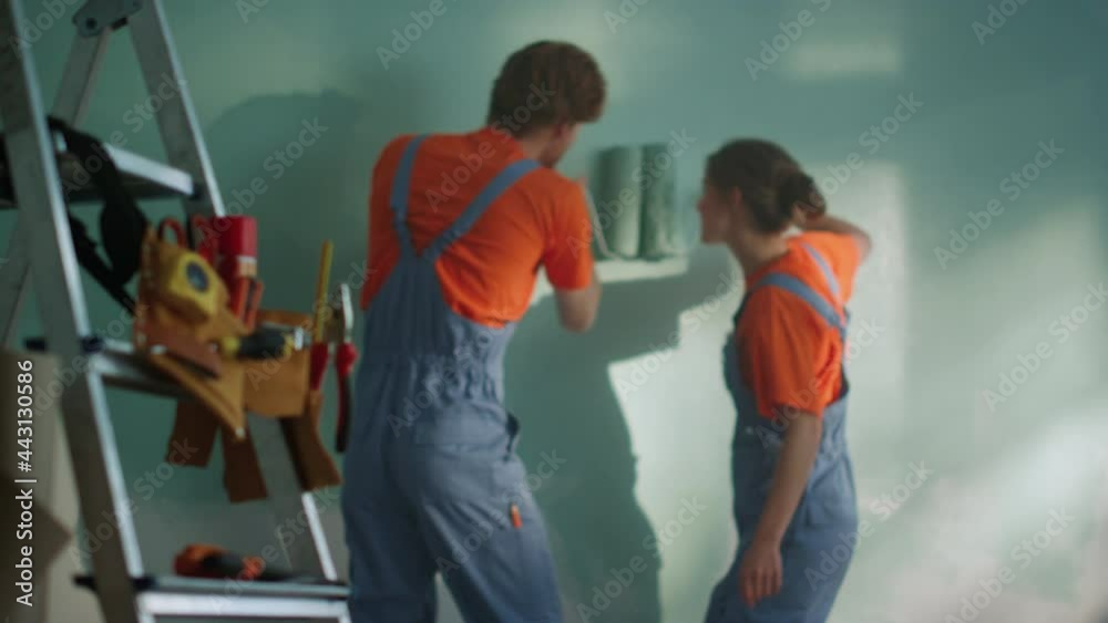 Cheerful woman diving under man hand indoors. Couple during home renovation.