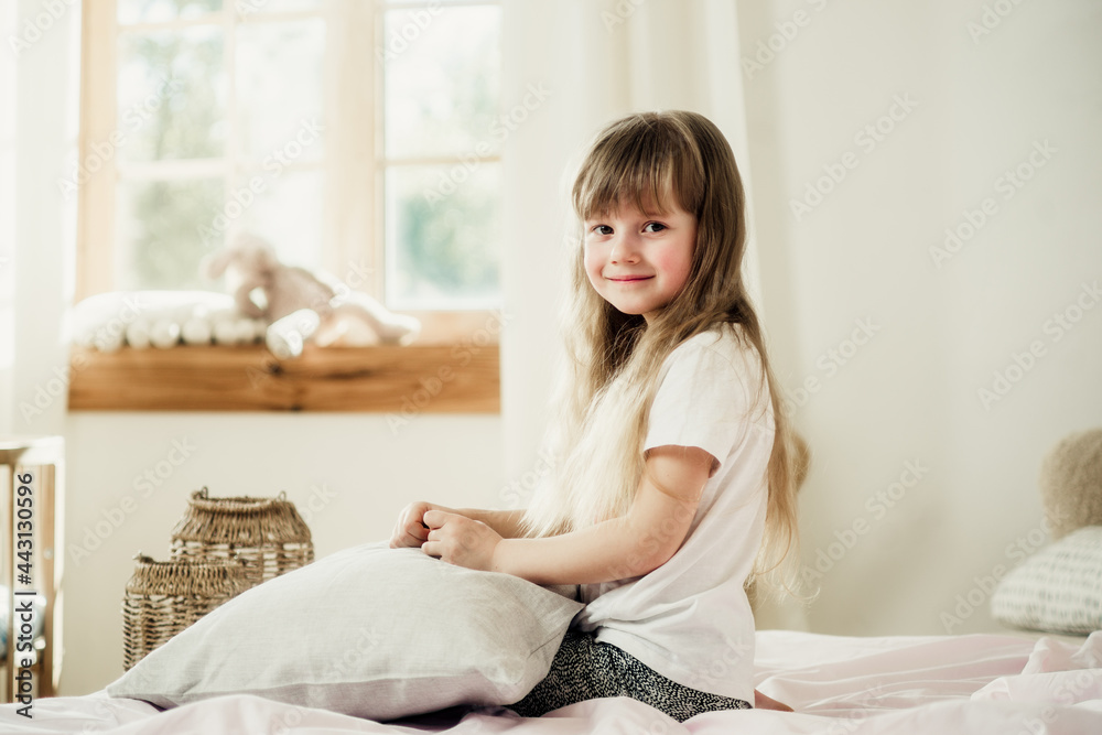 little girl sitting on the bed with a pillow little girl sitting on the bed with a pillow