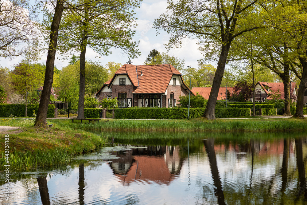 Dutch authentic house near the river with reflections in the water, surrounded by trees and greenery on a sunny day during spring in Grientsveen, The Netherlands