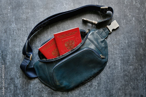 Green leather belt pouch with two international passports on a gray background, top view, closeup