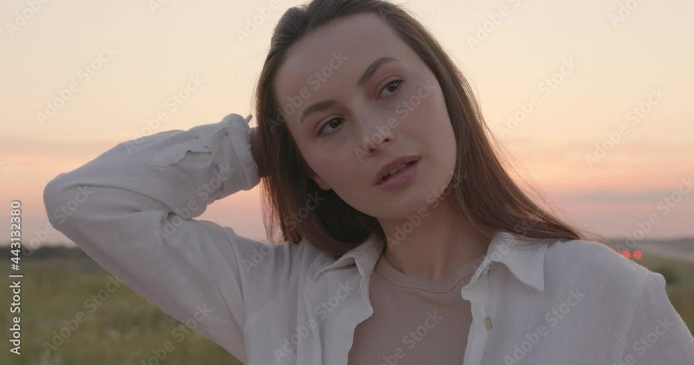 Portrait of pleasant woman with wavy brown hair standing outdoors with amazing sunset behind. Concept of freedom. Summertime joy. Portrait of pleasant woman with wavy brown hair standing outdoors with amazing sunset behind. Concept of freedom. Summertime joy.