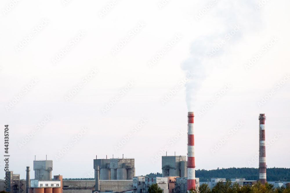 Factory chimneys against the gray autumn sky. Utopian landscape background. White toxic smoke is coming from a huge pipe. Pollution of the environment and nature. The collapse of civilization.