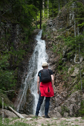 Portrait on back view of man looking anatural waterfall in the mountain photo