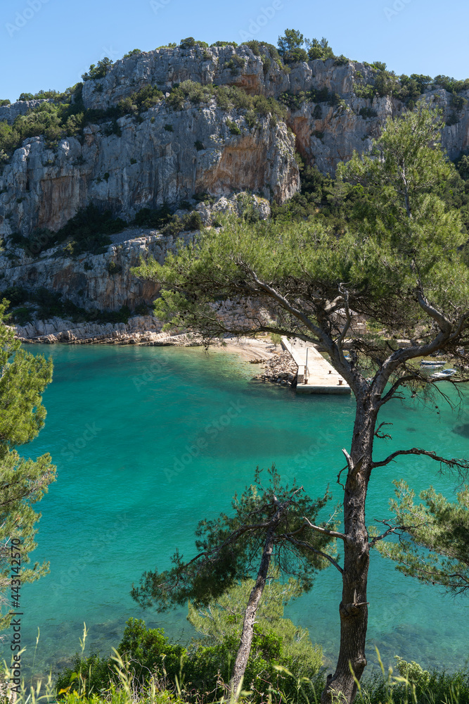 An atmospheric small rocky beach hidden between trees, rocks and turquoise sea water