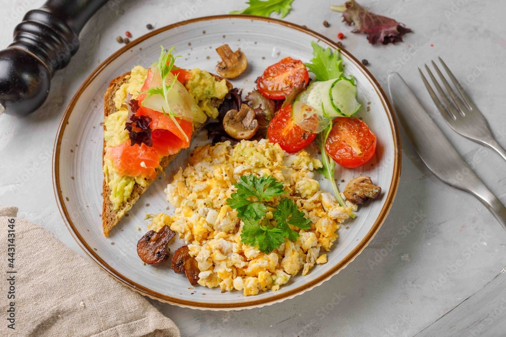 Nutritious breakfast, brunch. Scramble eggs, grilled vegetables and rye bread toast with avocado and smoked salmon. Close-up, horizontal Nutritious breakfast, brunch. Scramble eggs, grilled vegetables and rye bread toast with avocado and smoked salmon. Close-up, horizontal