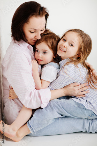 beautiful happy family sit on floor and cuddle in white photo studio.