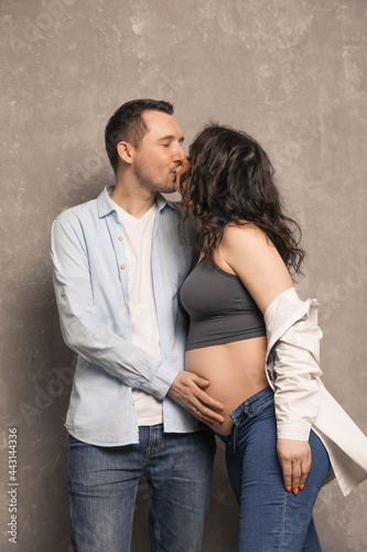 Beautiful happy couple is expecting a baby. A married couple expecting a child in a photo studio.