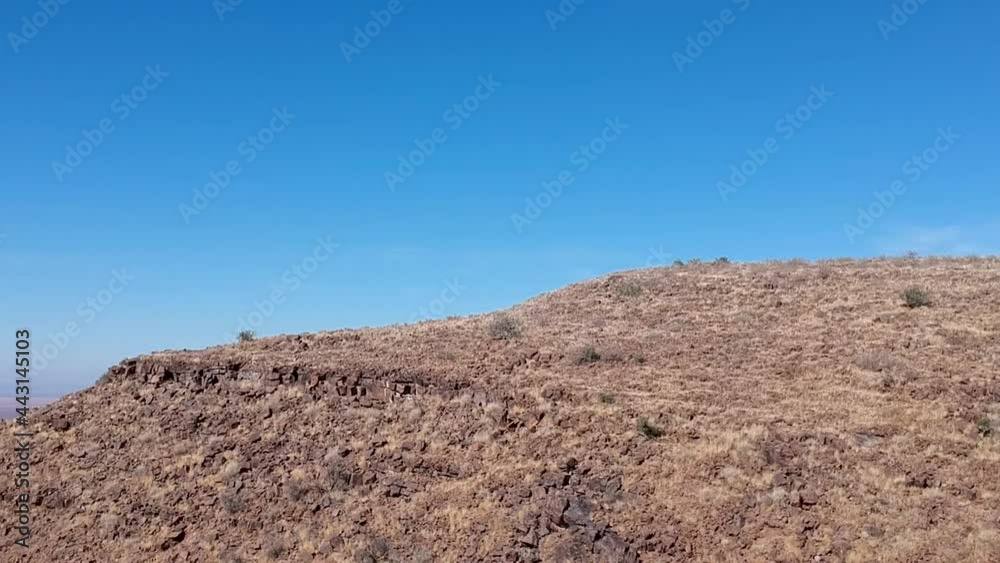 Desert hilltop with big desert plain in the background camera moving right to left to reveal the desert plain Aerial video Desert hilltop with big desert plain in the background camera moving right to left to reveal the desert plain Aerial video