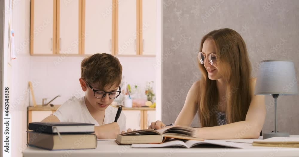 Mother and son are doing homework. Young teacher is studying with student. Tutor explains topic to child. Mother and son are doing homework. Young teacher is studying with student. Tutor explains topic to child.
