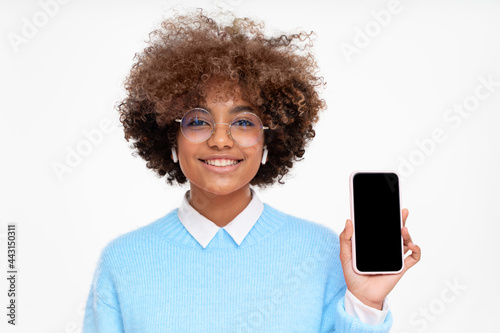 African female teen showing smart phone with blank screen with copy space, isolated on gray background
