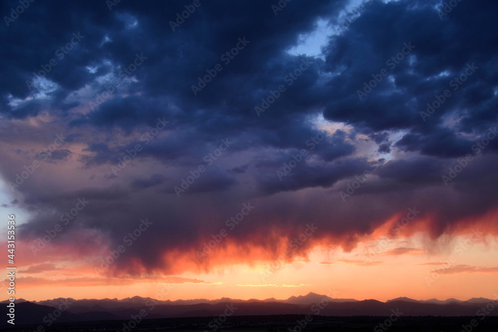 dramatic virga clouds at sunset over the front range of the colorado rocky mountains, as seen from broomfield, colorado 