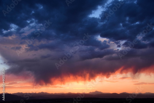 dramatic virga clouds at sunset over the front range of the colorado rocky mountains, as seen from broomfield, colorado  © Nina